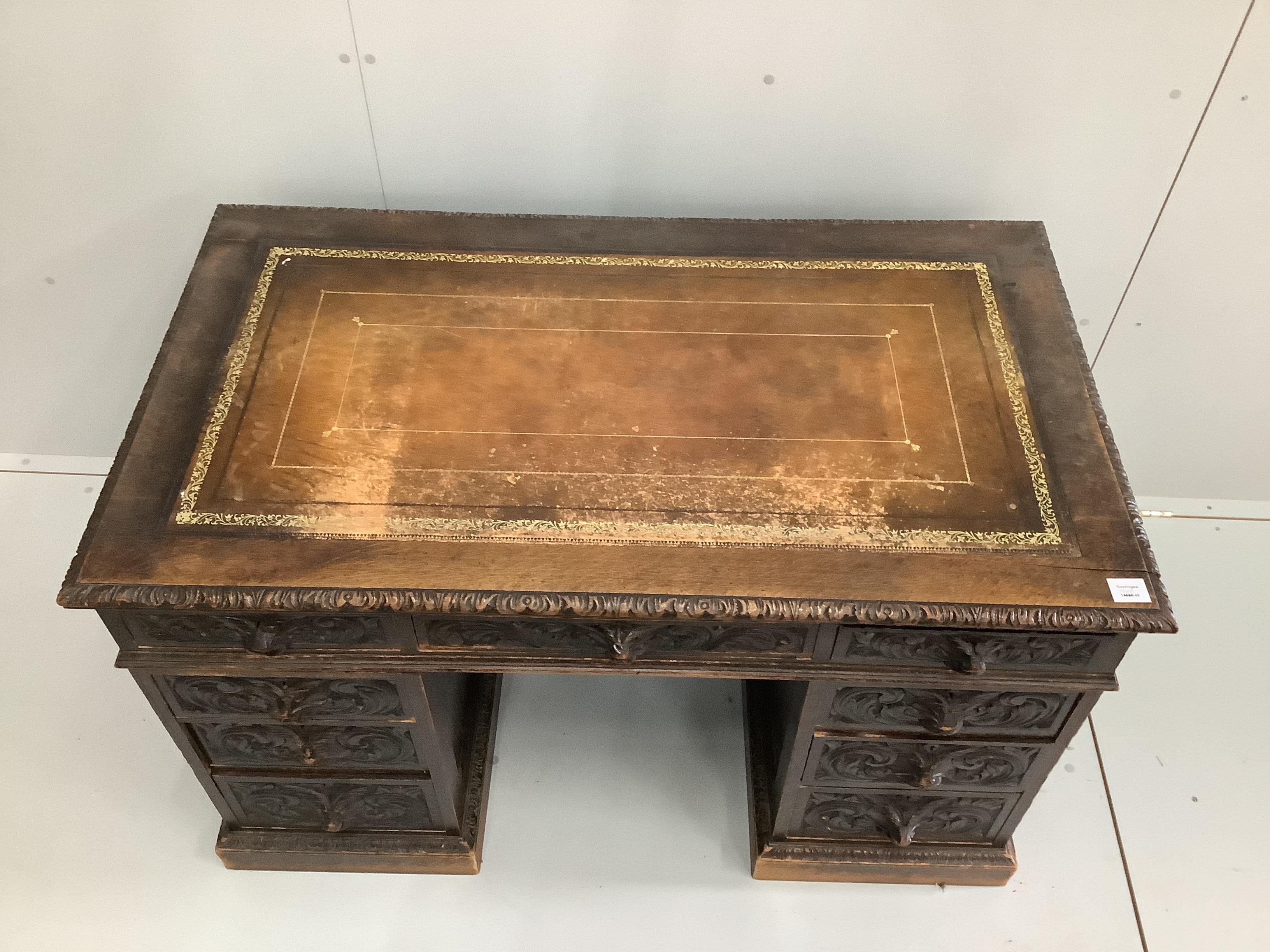 A late Victorian carved oak pedestal desk with lion mask cup handles, width 122cm, depth 70cm, height 75cm
